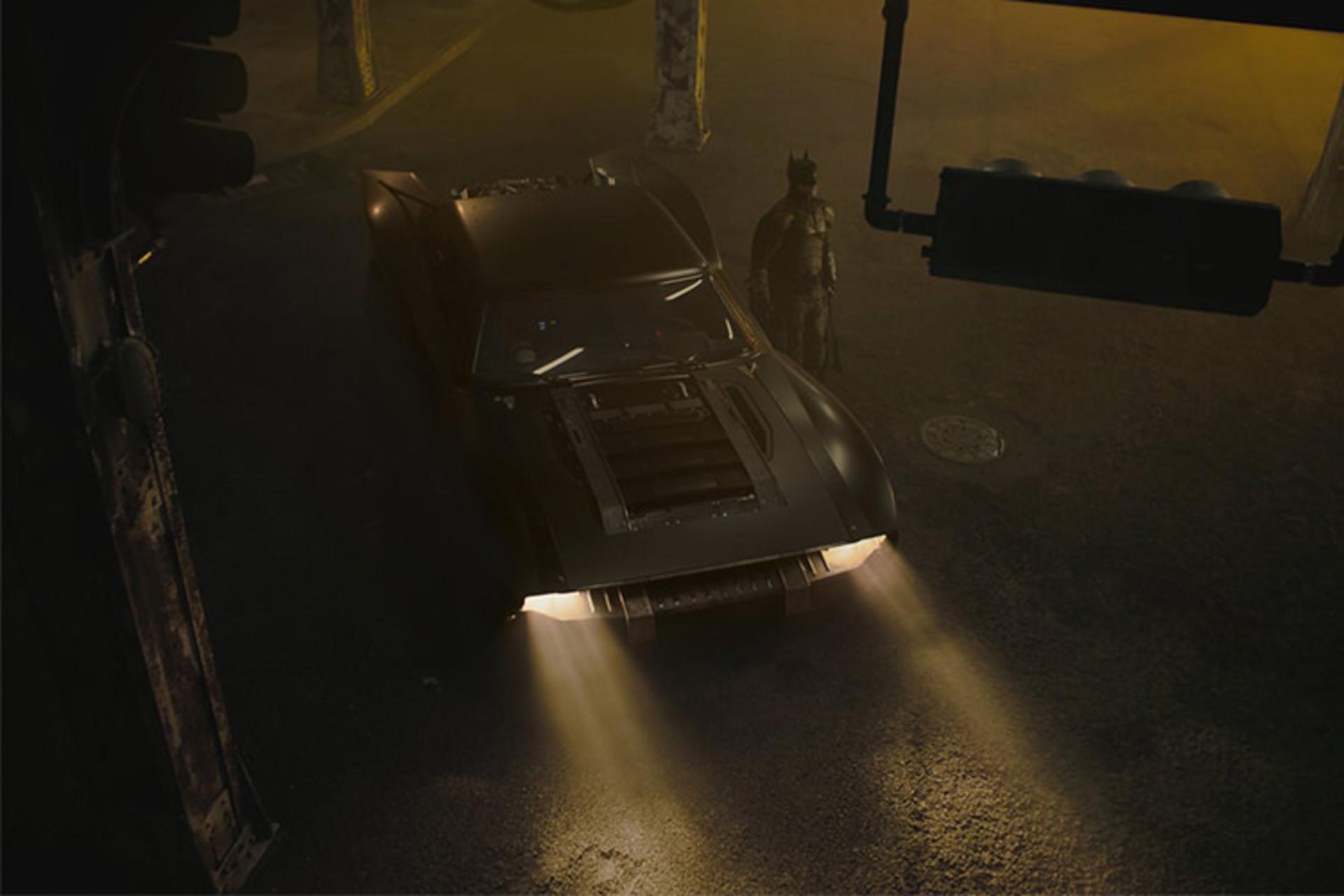 بتموبیل با نور زرد چراغ های در کنار بتمن در فیلم The Batman با بازی رابرت پتینسون