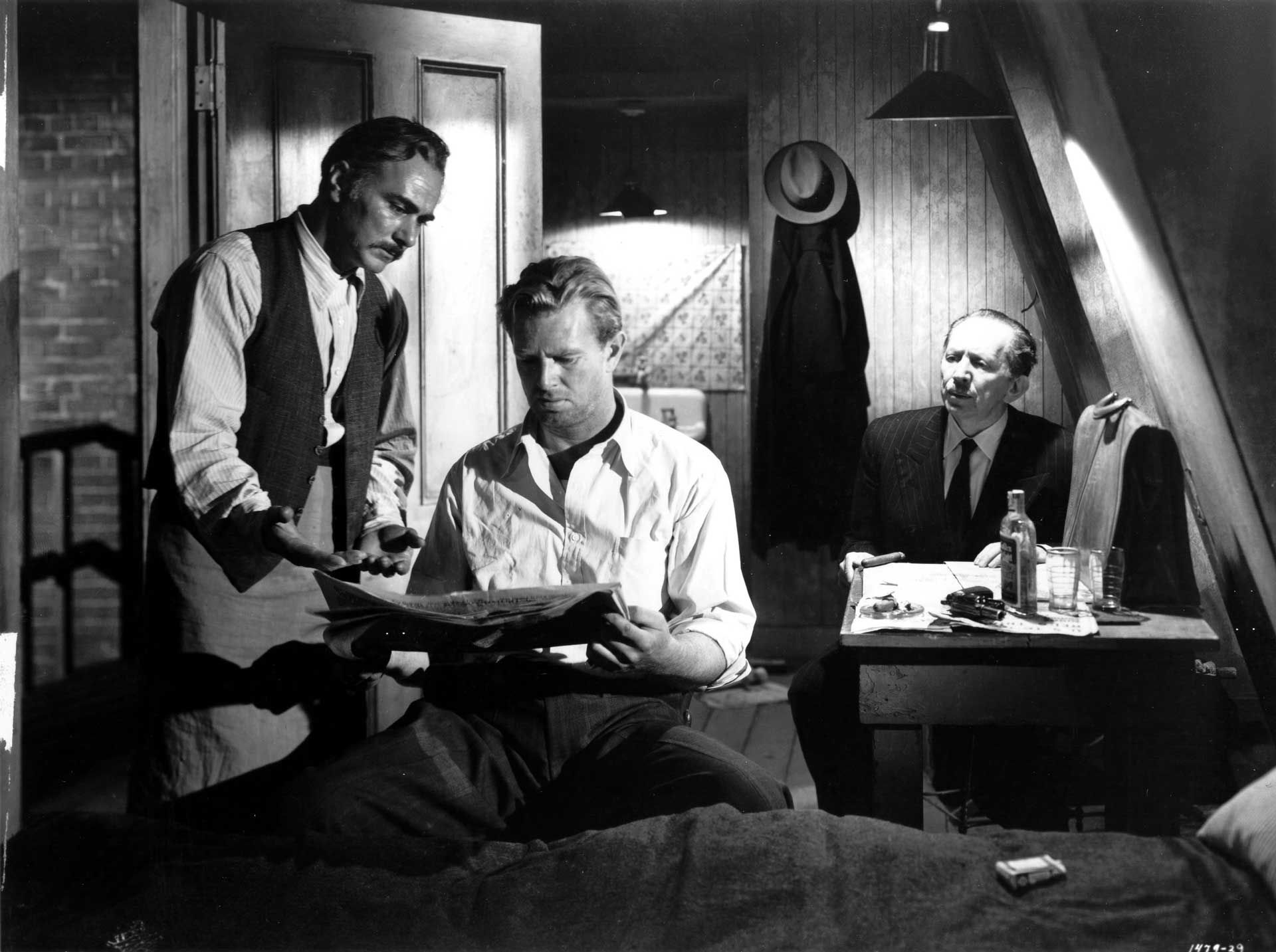 فیلم The Asphalt Jungle و مرد در حال بررسی برگه ها در کنار چند نفر دیگر