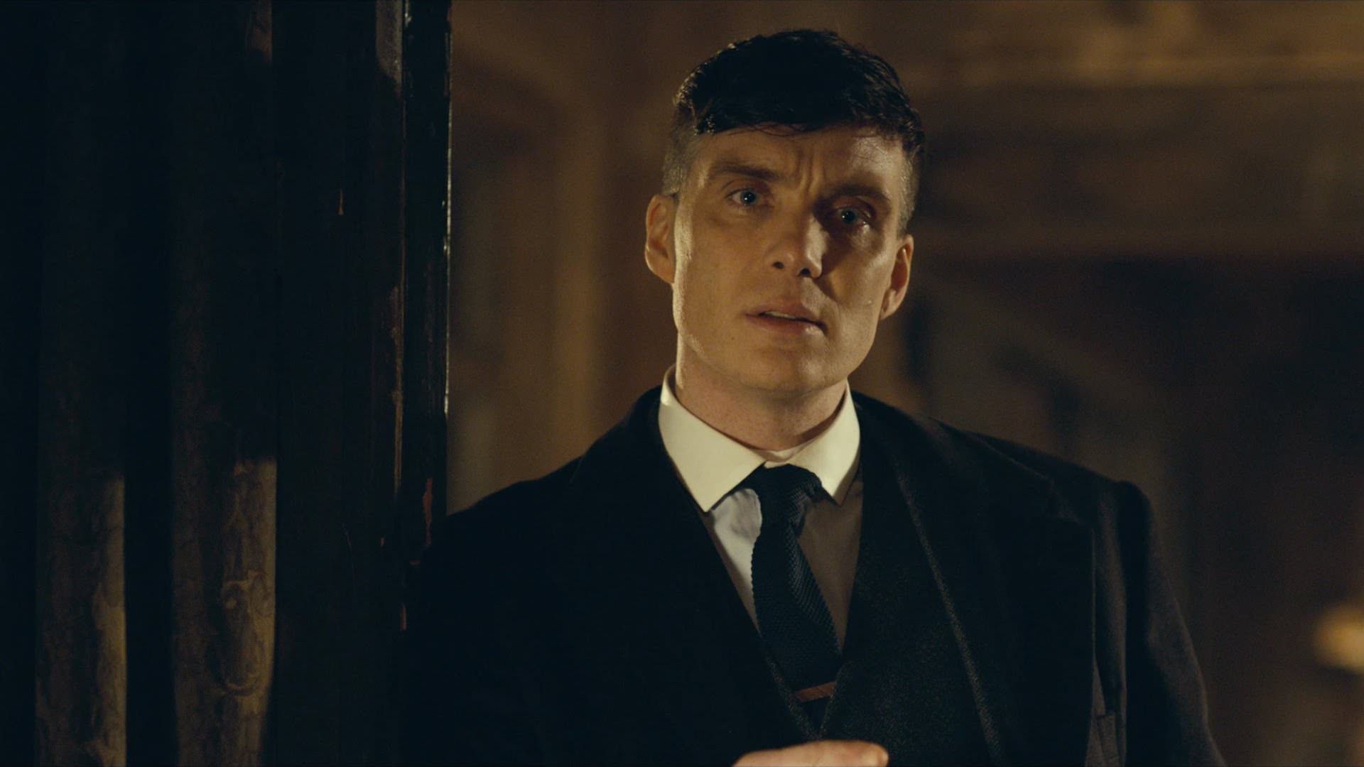 کیلین مورفی در نقش تامی شلبی تکیه داده به در سریال Peaky Blinders 