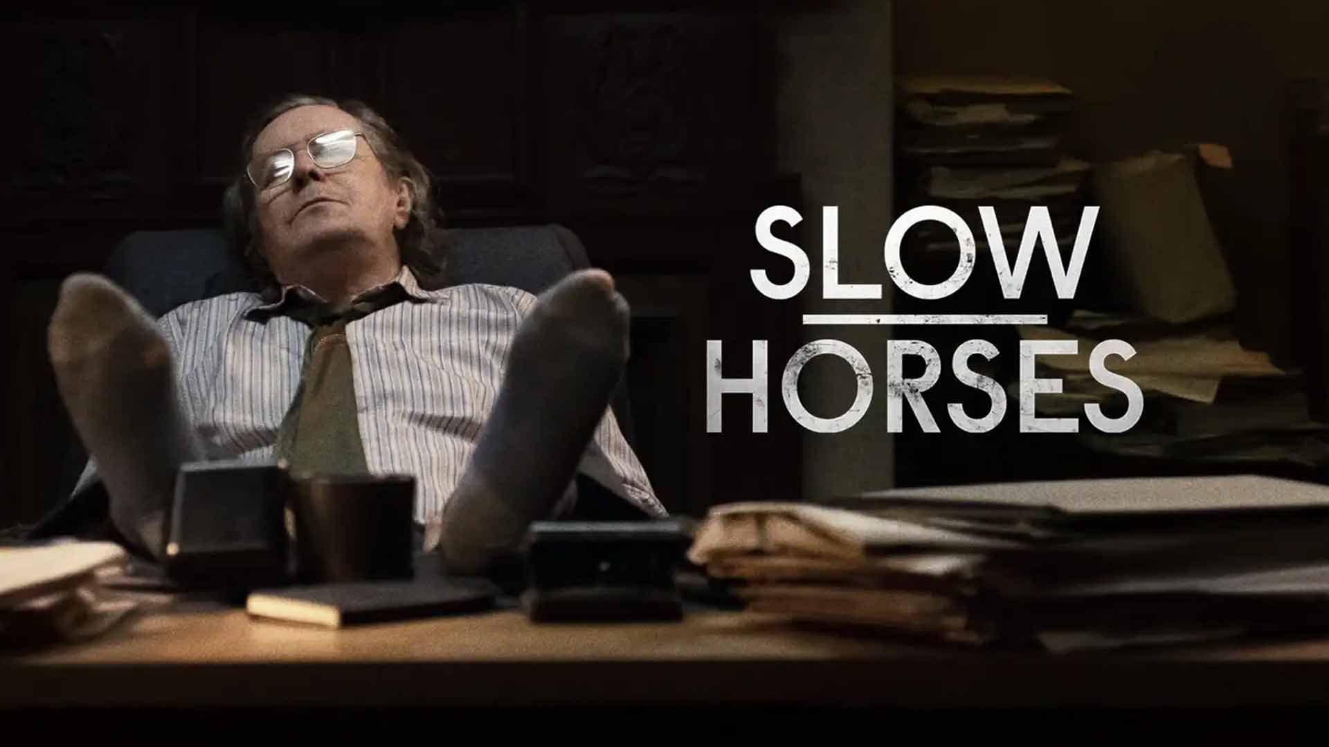 گری اولدمن در پوستر سریال Slow Horses پاهای خود را روی میز انداخته است