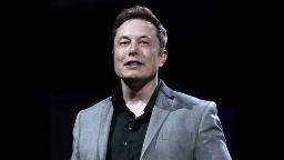 ایلان ماسک (Elon Musk) با کت خاکستری در یک رویداد رسمی