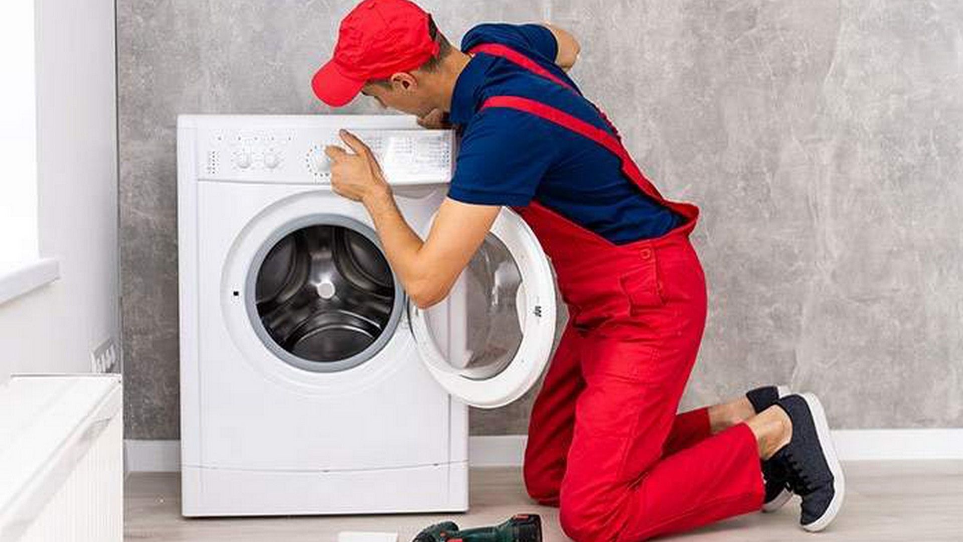 تصویر یک تعمیرکار ماشین لباس‌شویی درحال تعمیر 