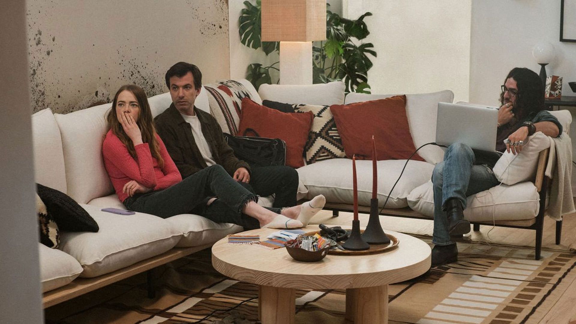 اما استون و نیتن فیلدر داخل اتاق پذیرایی یک خانه روی یک مبل نشسته‌اند و به جایی خارج از قاب نگاه می‌کند در حالی که کمی آن‌طرف‌تر بنی سفدی به لپ‌تاپش خیره است در نمایی از سریال نفرین به کارگردانی نیتن فیلدر