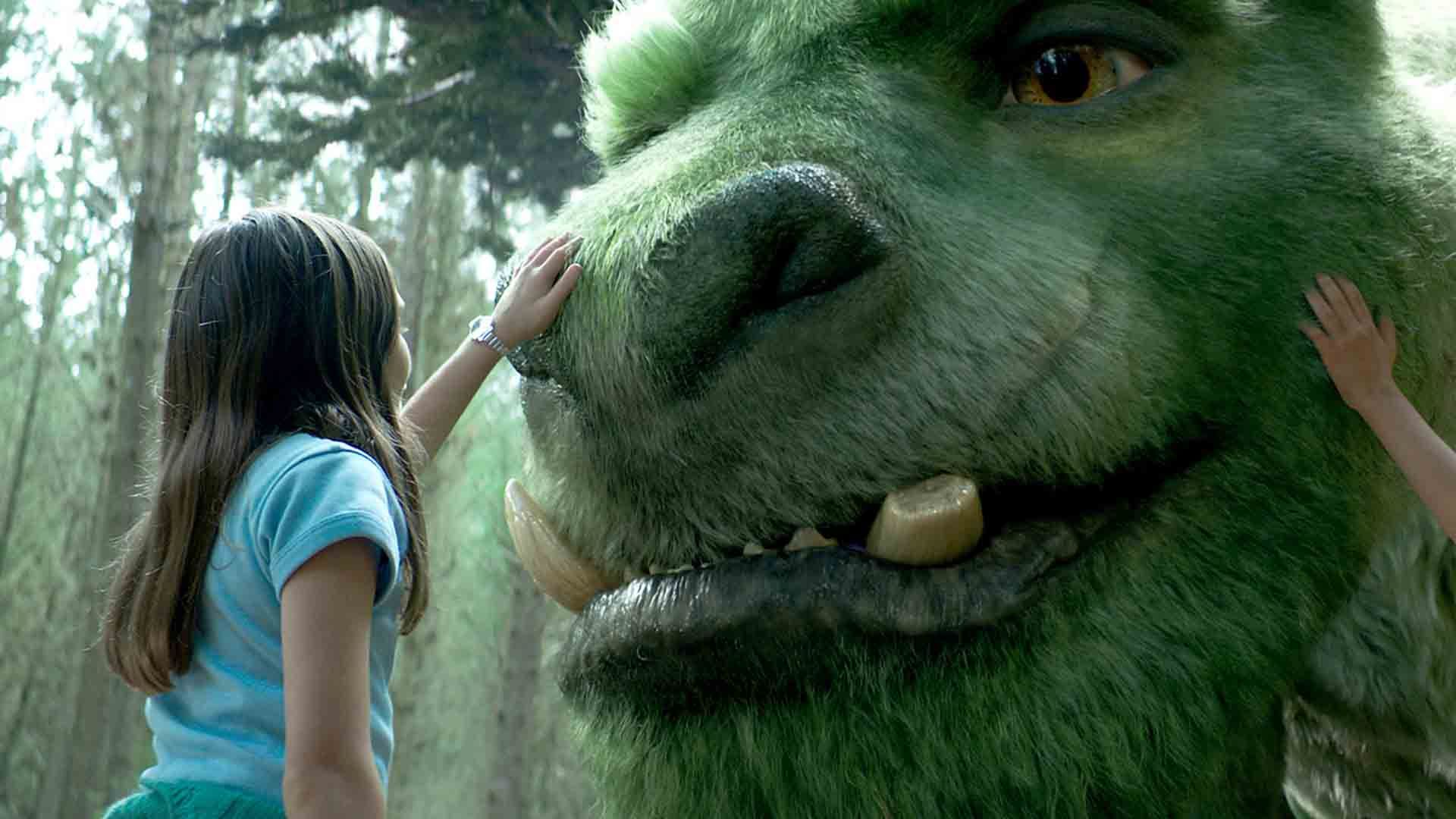 دختر بچه‌ای در فیلم Pete’s Dragon دستش روی صورت اژدها گذاشته است