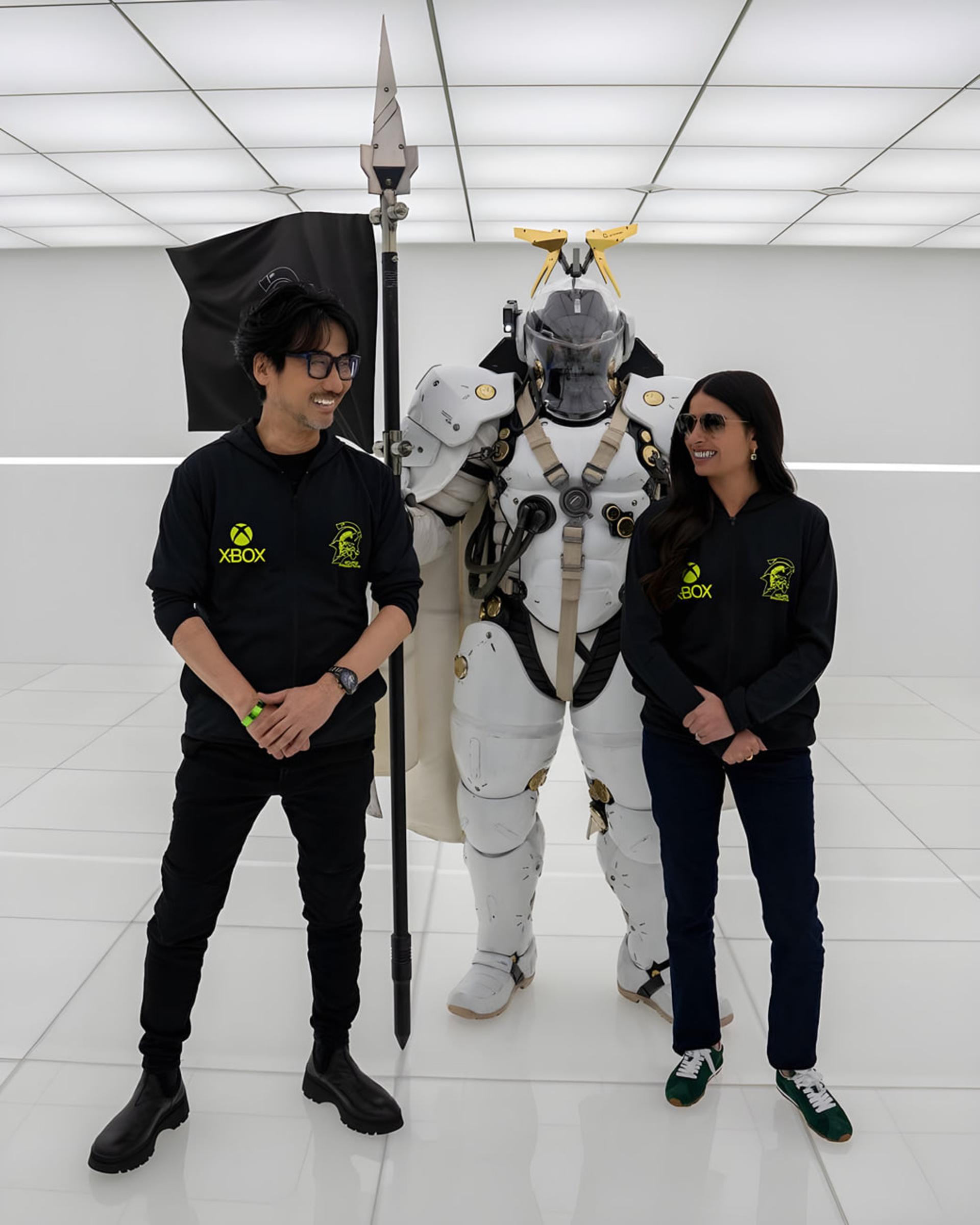 آشا شارما (Asha Sharma) در کنار هیدئو کوجیما (Hideo Kojima) و شخصیت زرهپوش در استودیو