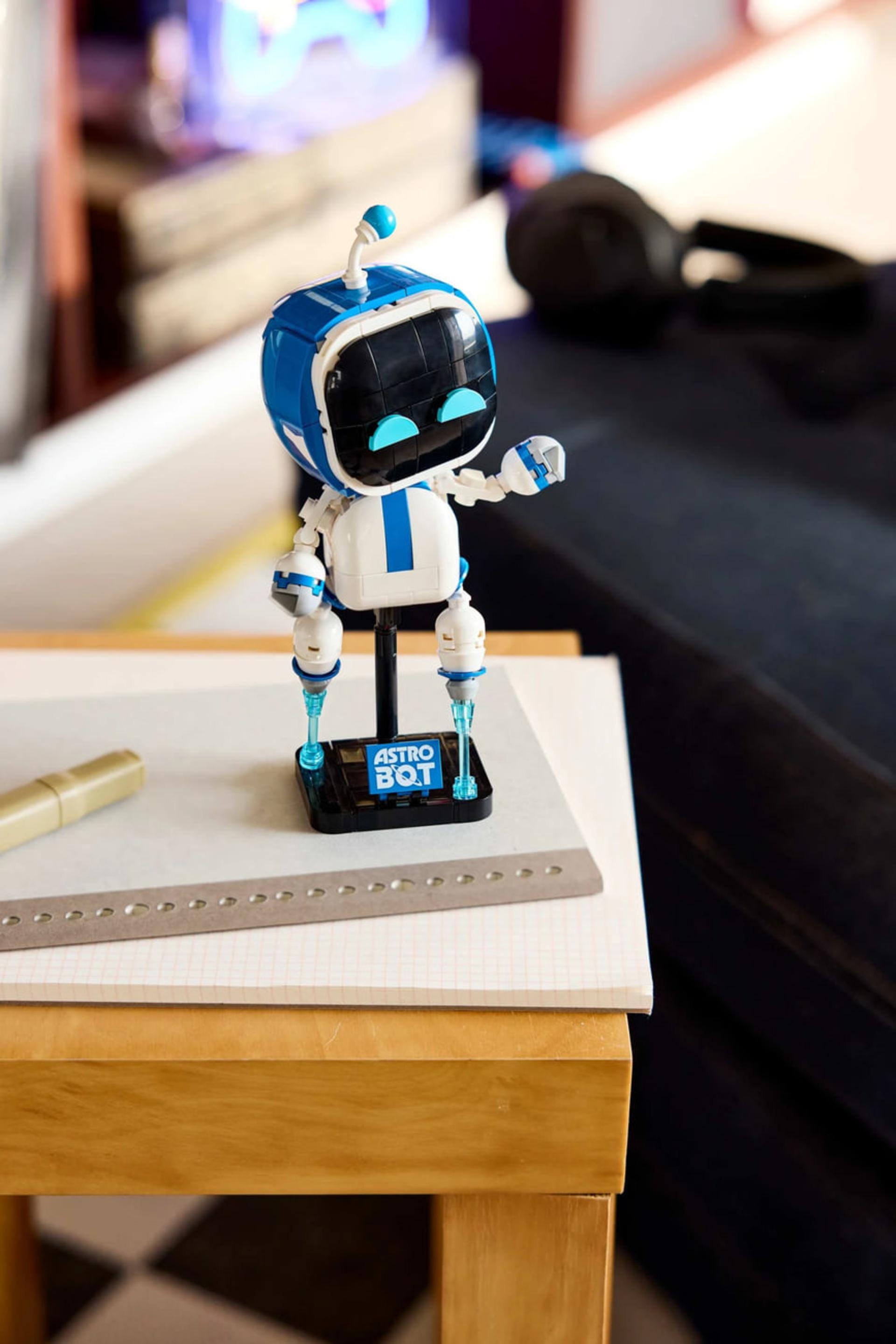 مجسمه کوچک ربات آسترو بوت (Astro Bot) روی یک دفترچه سفید