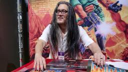 جان رومرو در کنار پوسترهای بازی DOOM