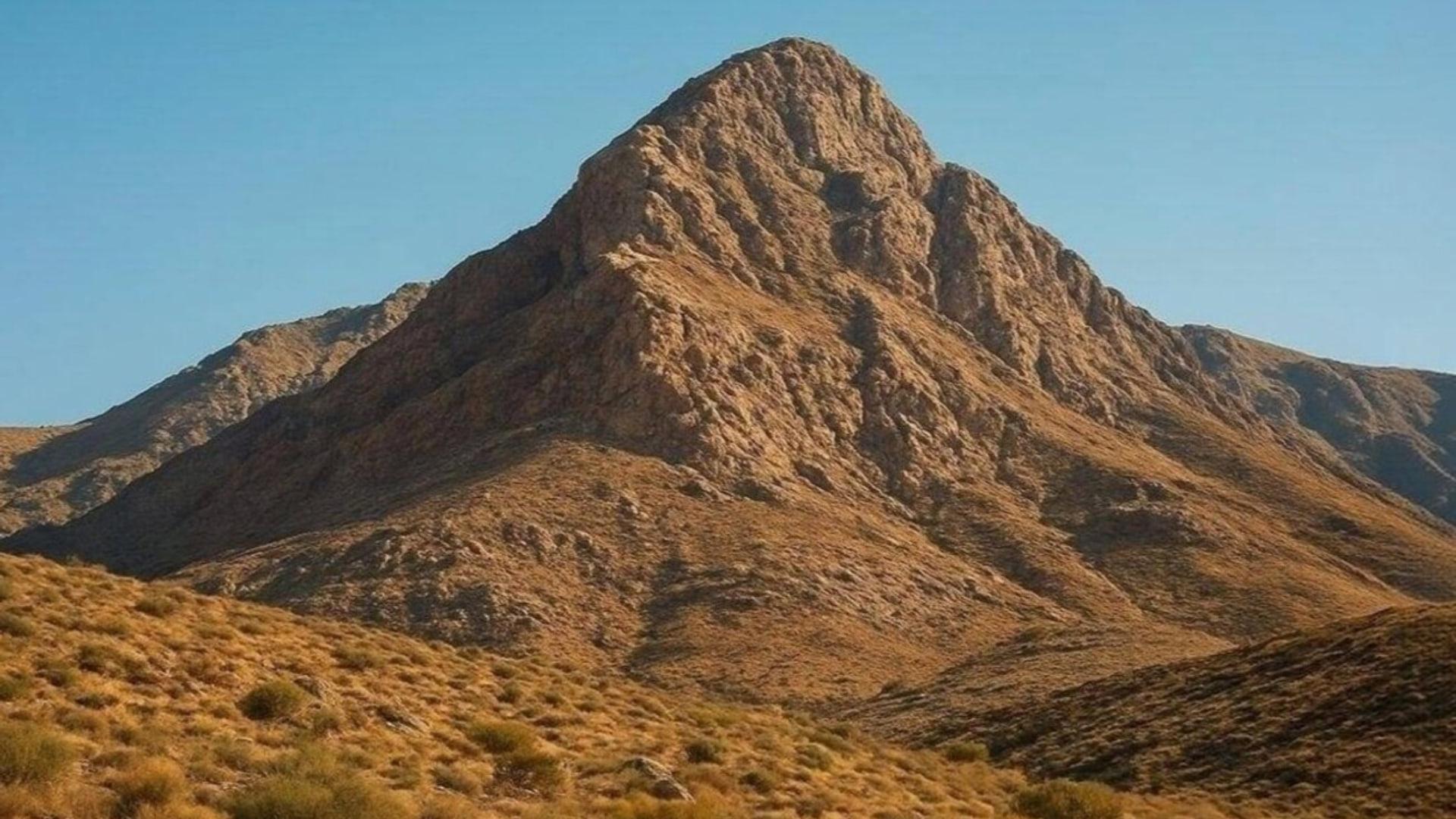 نمای نزدیک و عریض از کوه کلنگ با شیب‌های صخره‌ای و پوشش گیاهی خشک زیر آسمان صاف