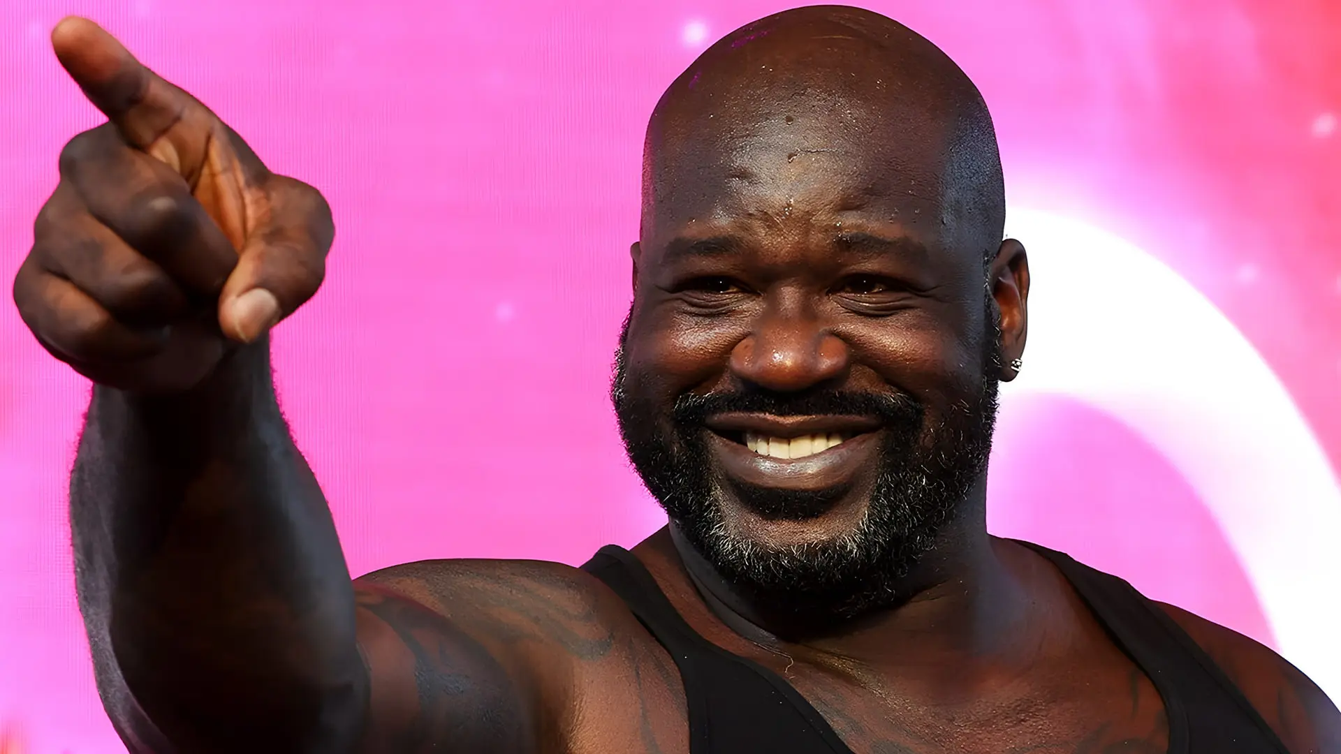 شکیل اونیل (Shaquille O'Neal) با لبخند و دست اشاره شده در مقابل پس‌زمینه صورب