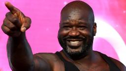 شکیل اونیل (Shaquille O'Neal) با لبخند و دست اشاره شده در مقابل پس‌زمینه صورب