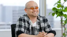 هیدکی کامییا (Hideki Kamiya) با عینک نارنجی در حال لبخند زدن