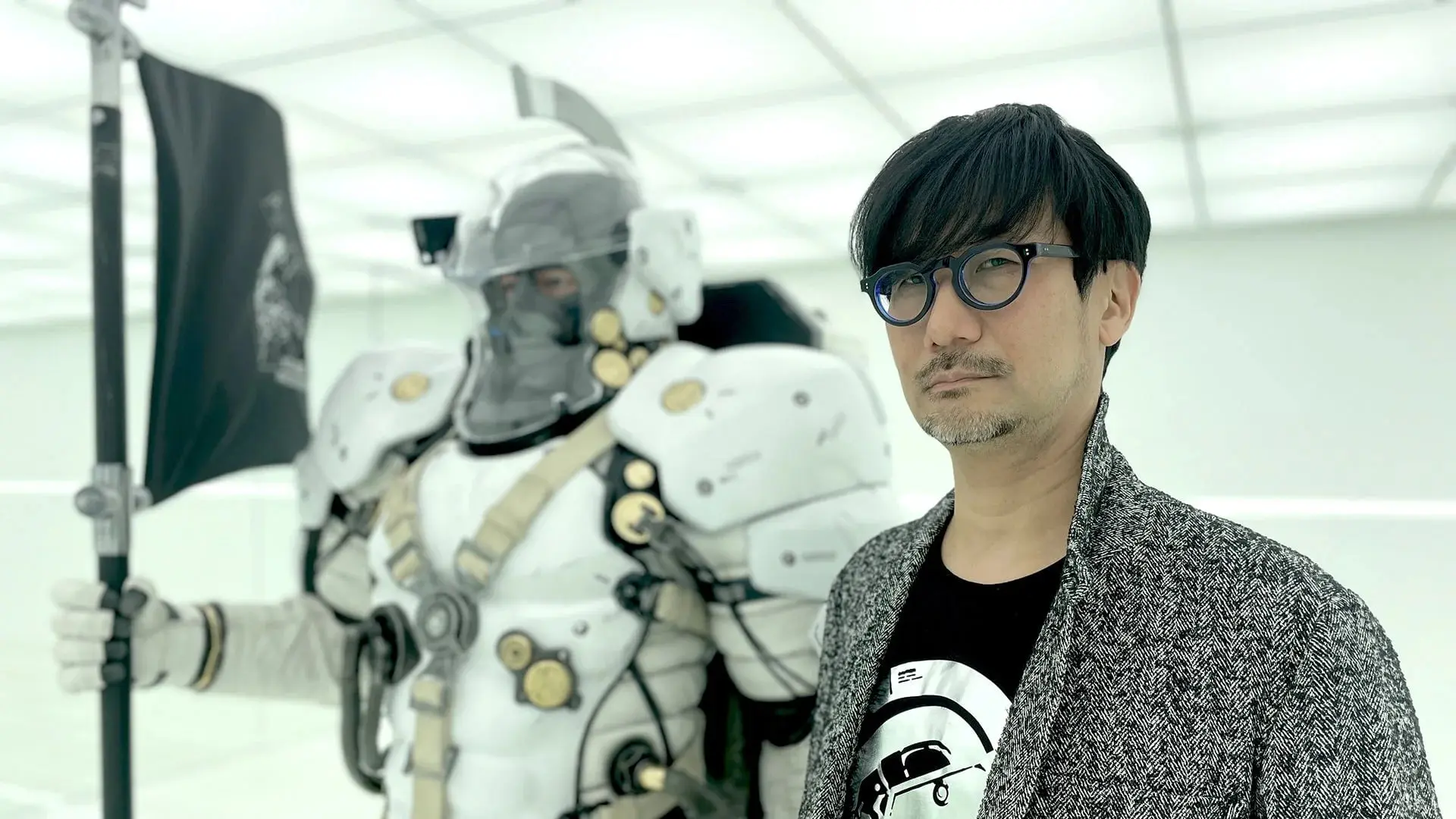 هیدئو کوجیما (Hideo Kojima) در کنار شخصیت با لباس زره سفید بازی Physint