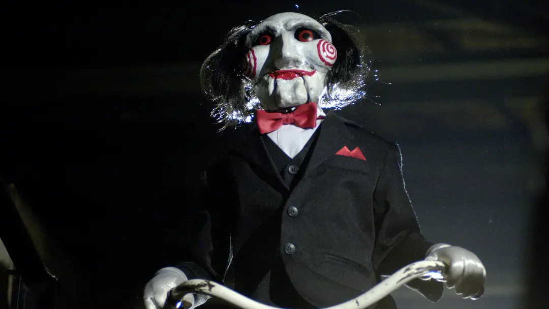 عروسک ماسک‌دار شخصیت جیگسو (Jigsaw) با کت مشکی و پاپیون قرمز
