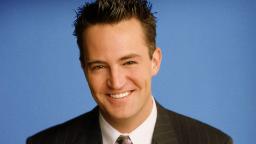 متیو پری (Matthew Perry) بازیگر سریال دوستان با لبخند در مقابل پس‌زمینه آبی