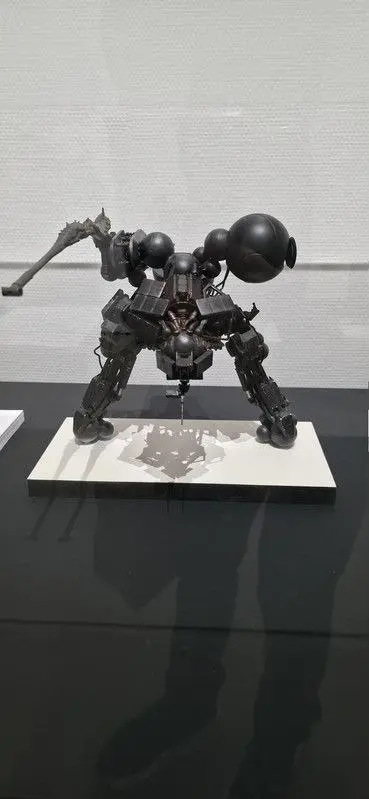 مجسمه رباتیک از سری بازی‌های متال گیر (Metal Gear) روی پایه سفید