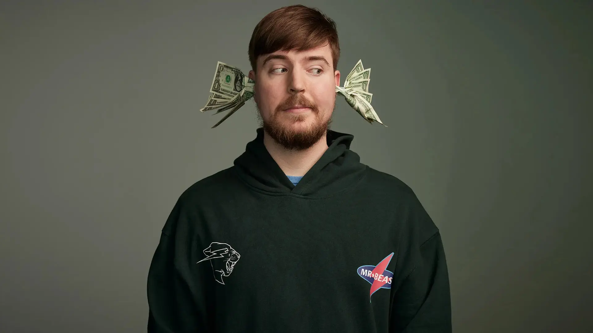 مستربیست (MrBeast) با اسکناس‌های دلار در گوش‌های خود