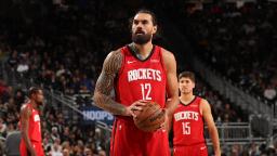 بازیکن تیم راکتس (Houston Rockets) با لباس قرمز در حال نگه داشتن توپ بسکتبال