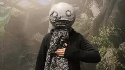 ماسک سفید و گرد با چهره‌ای خندان بر صورت خالق بازی Nier Automata