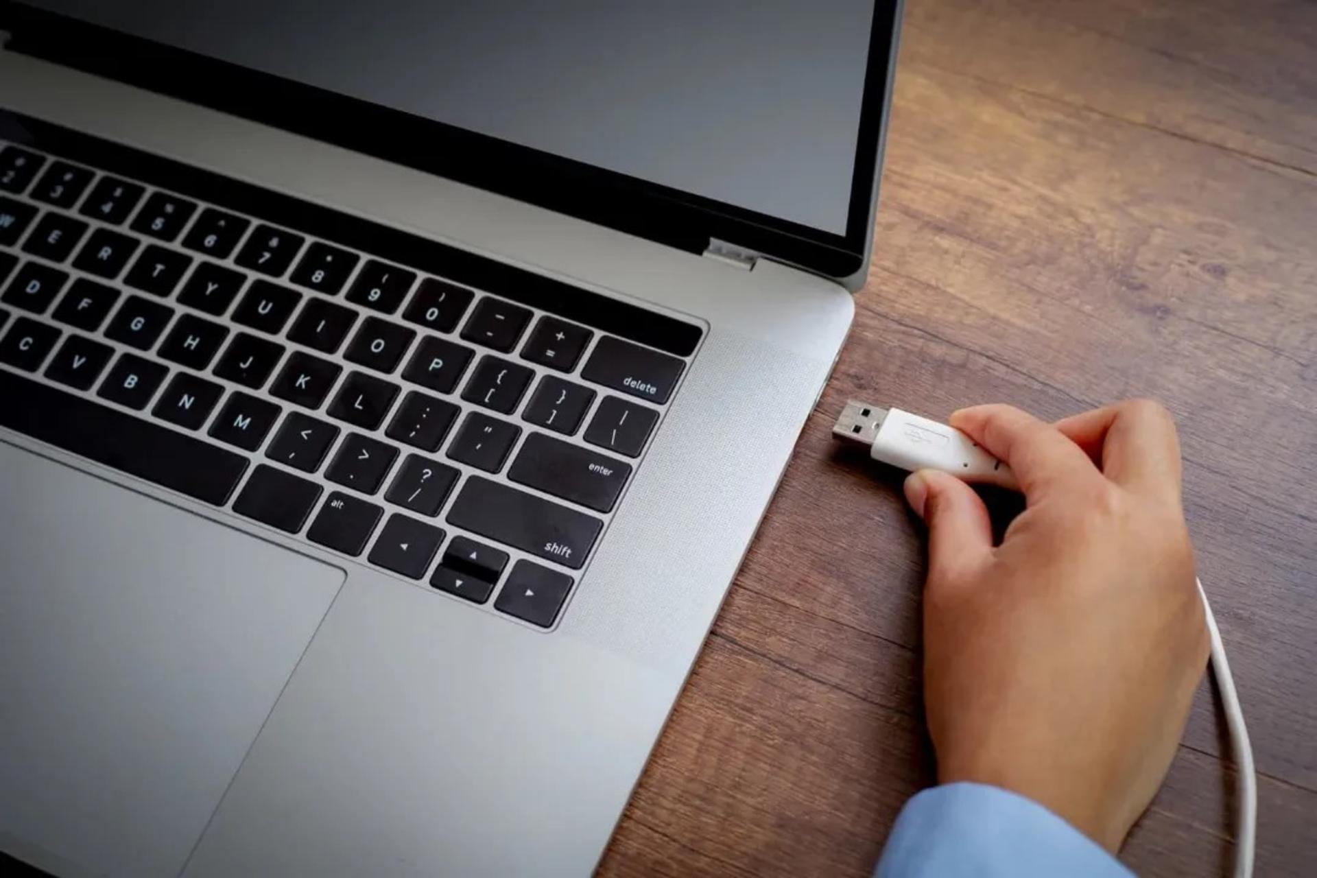 شخصی درحال وصل‌کردن کابل USB-A به لپ‌تاپ