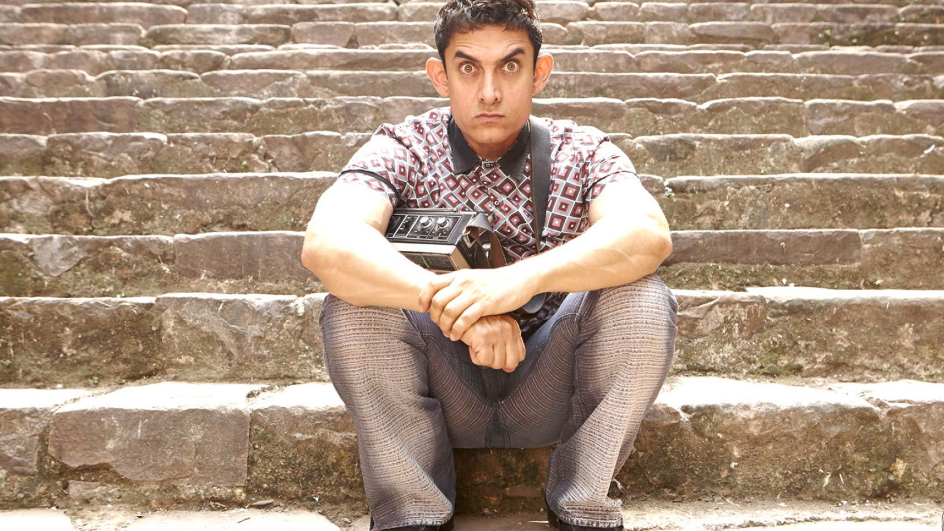 PK_aamir_khan_sitting_on_stairs_wirh_wided_eyes