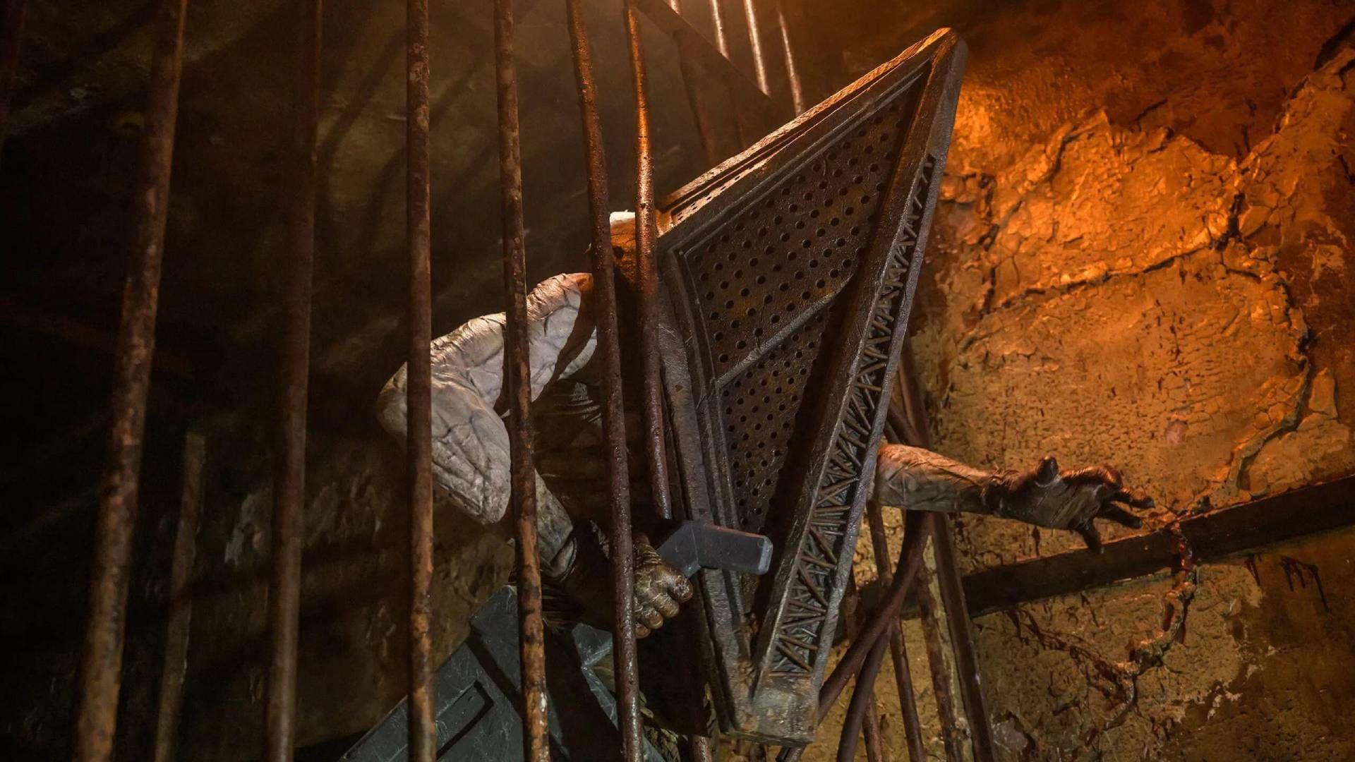 شخصیت پیرامید هد (Pyramid Head) در حال عبور از میان میله‌های آهنی سایلنت هیل