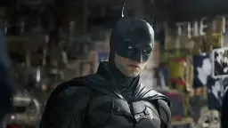 بتمن (Batman) با لباس زرهی سیاه در محیطی تاریک