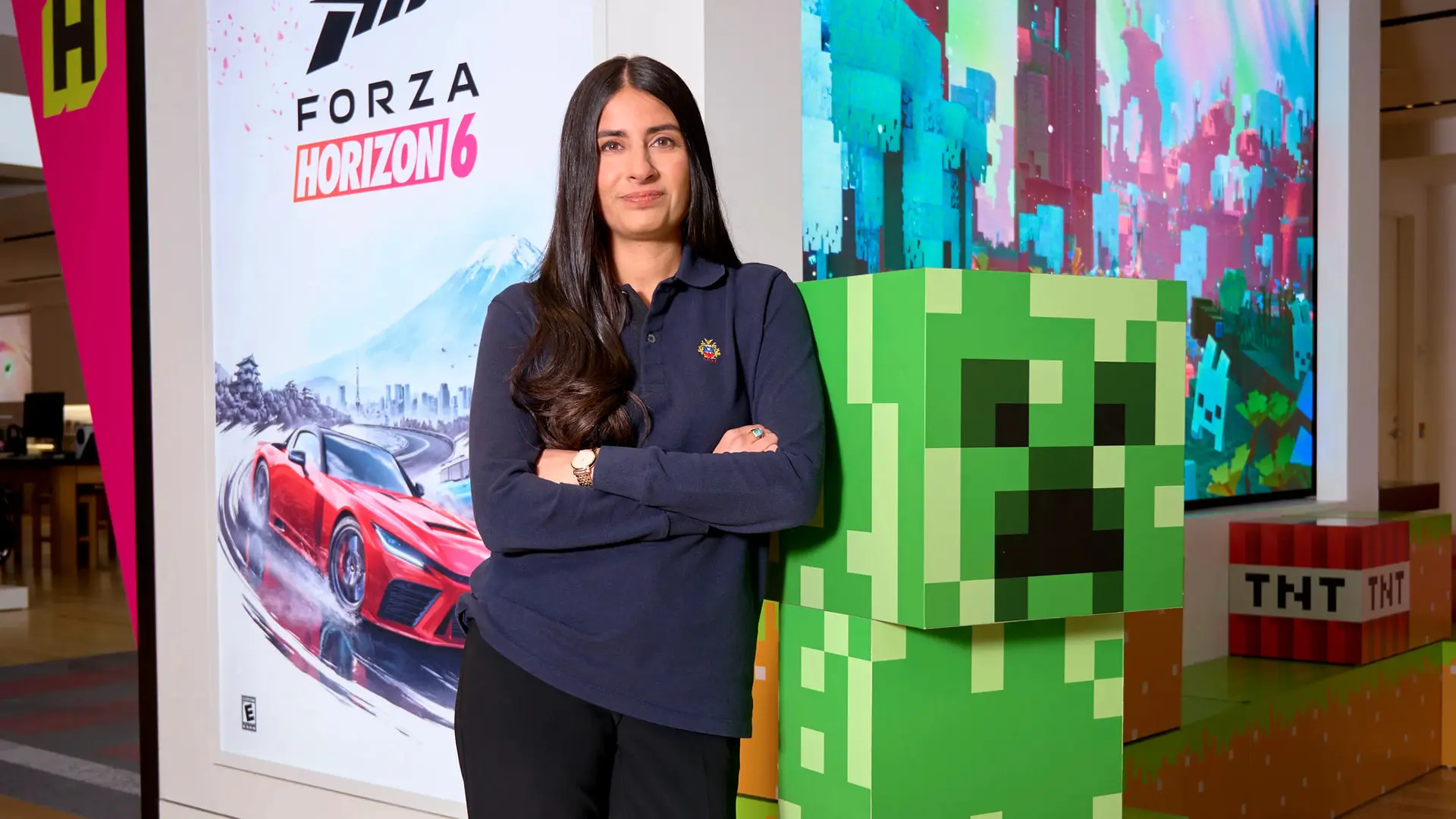 آشا شارما (Asha Sharma) در کنار پوسترهای بازی‌های ایکس باکس (Xbox) در فروشگاه مایکروسافت