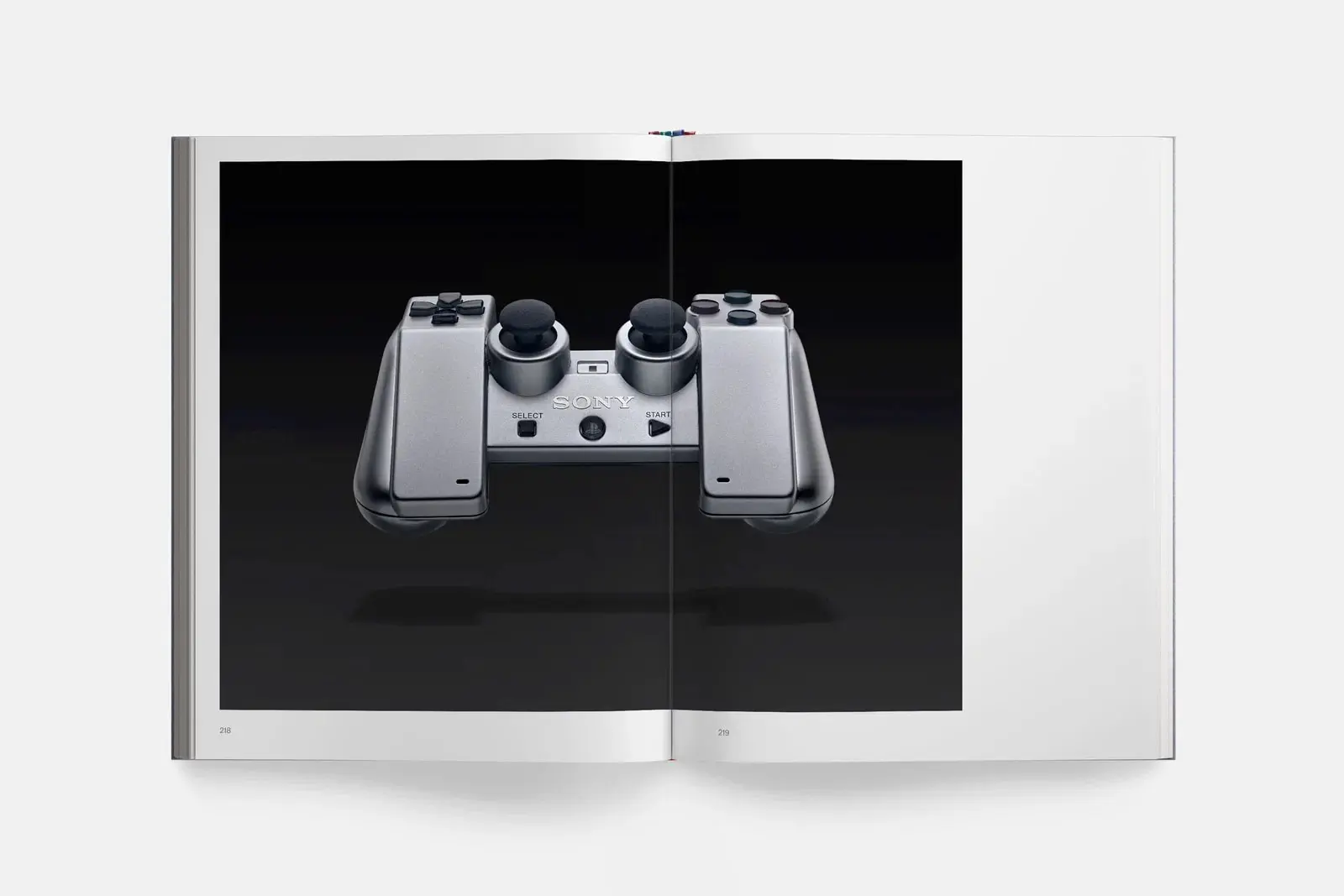 دسته بازی کنسول پلی‌استیشن (PlayStation) با رنگ نقره‌ای روی صفحه سیاه