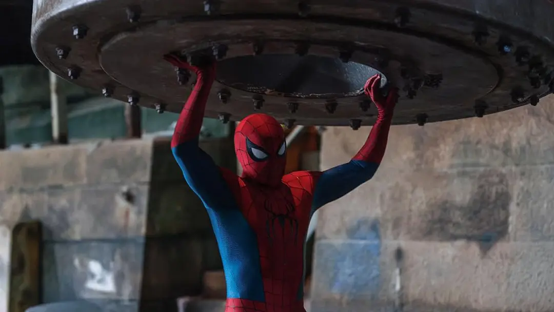 مرد عنکبوتی (Spider-Man) در حال نگه داشتن یک قطعه فلزی بزرگ