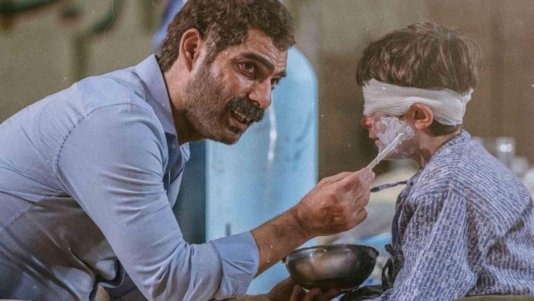 پیمان معادی در کنار یک کودک زخمی در فیلم درخت گردو