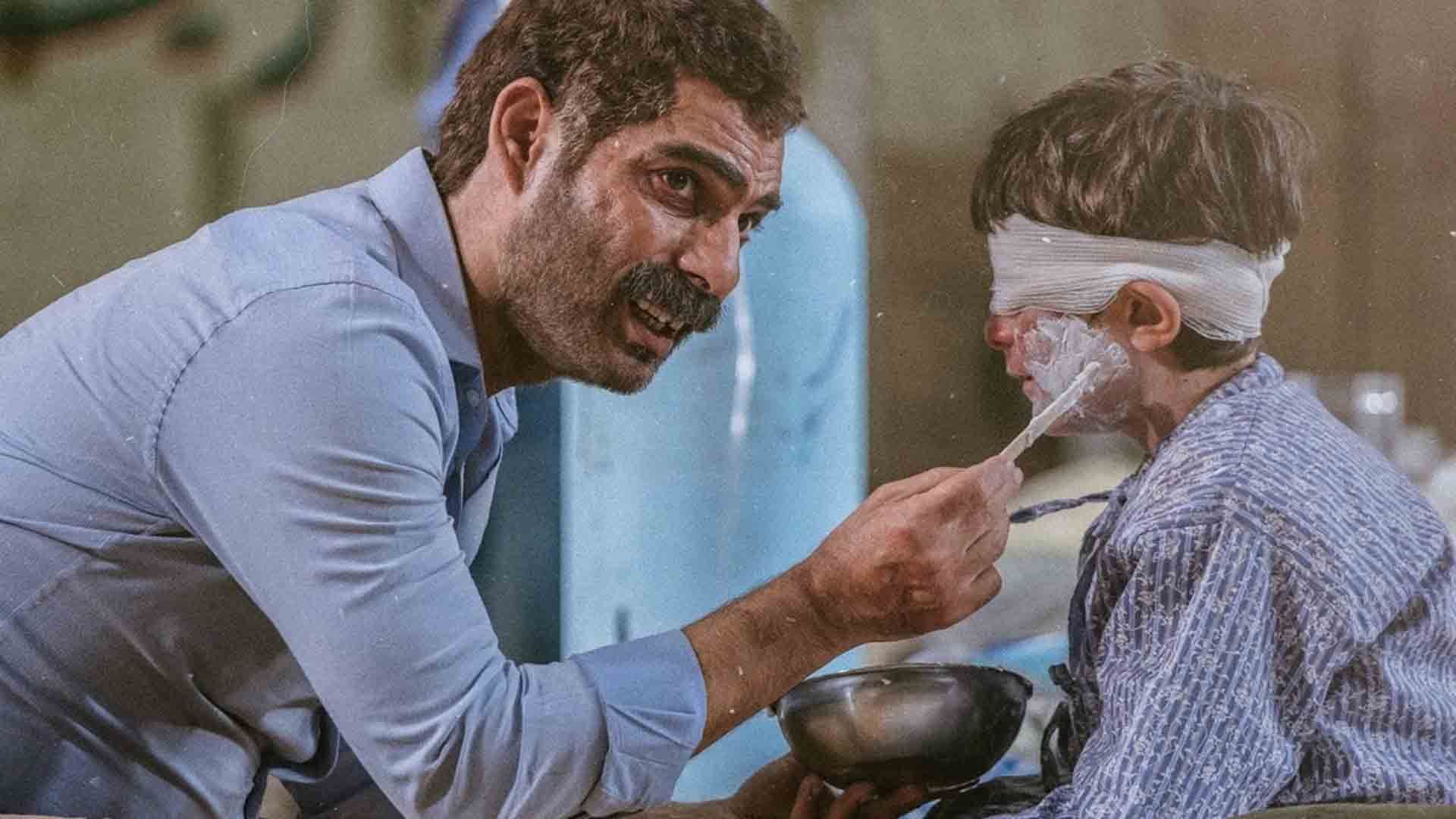پیمان معادی در کنار یک کودک زخمی در فیلم درخت گردو
