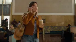 زن جوان در حال استفاده از ایرپاد (AirPods) در محیط ایستگاه یا فرودگاه